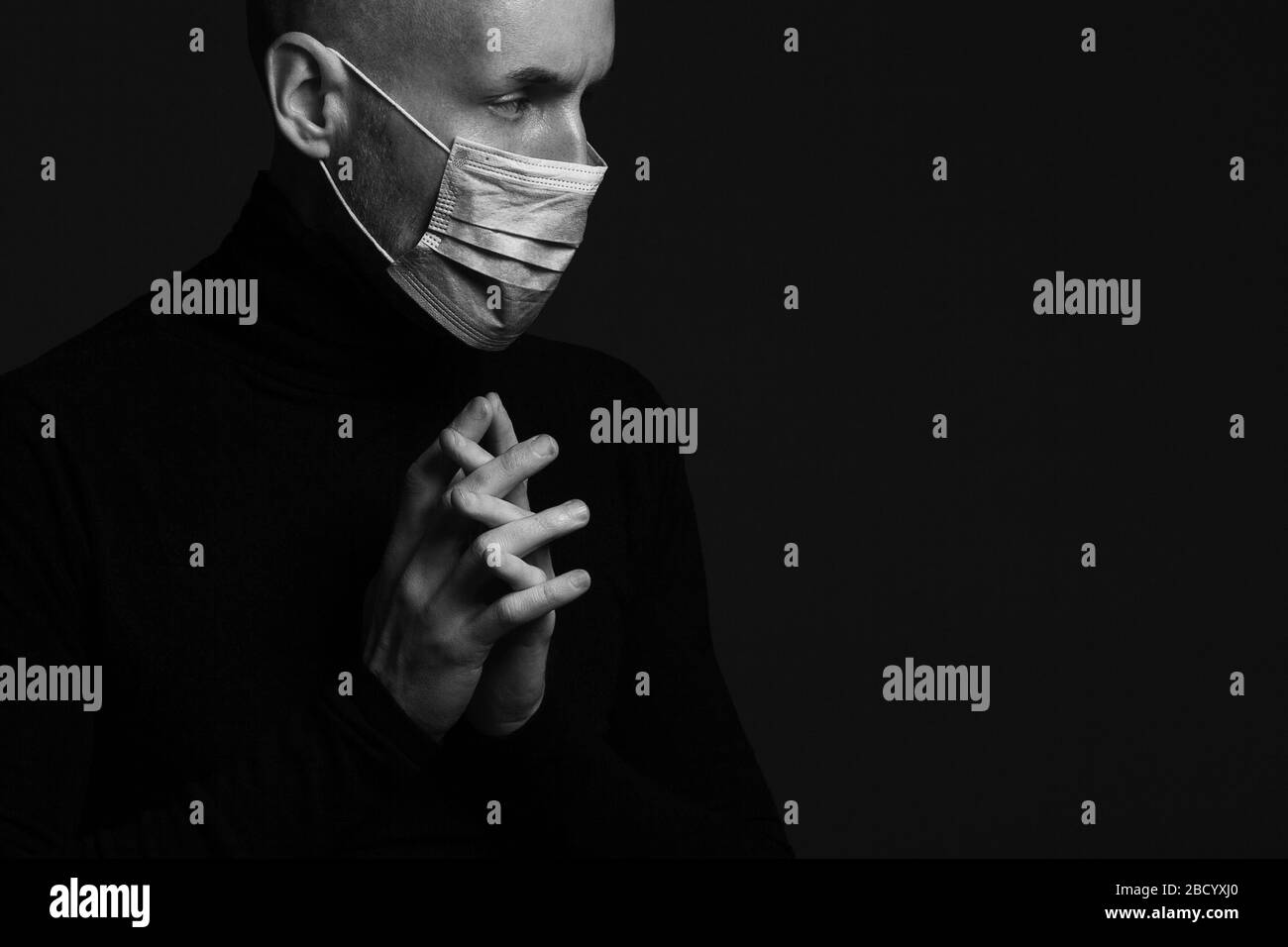 Coronavirus, Bio-Schutz-Konzept. Nahaufnahme Profil Porträt von schönen Glatze Mann trägt medizinische Maske, schwarzen Rollkragen und beten. Kopierbereich. St Stockfoto