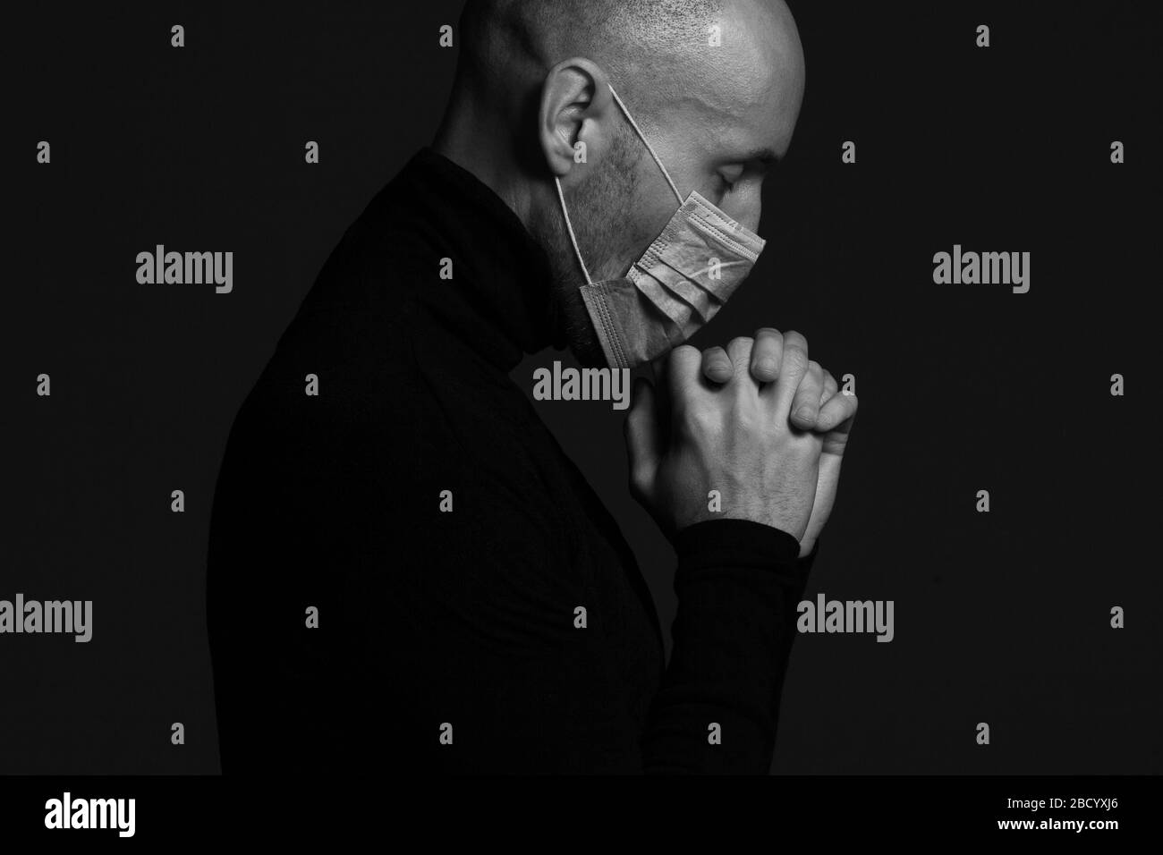 Coronavirus, Bio-Schutz-Konzept. Nahaufnahme Profil Porträt von schönen Glatze Mann trägt medizinische Maske, schwarzen Rollkragen und beten. Kopierbereich. St Stockfoto