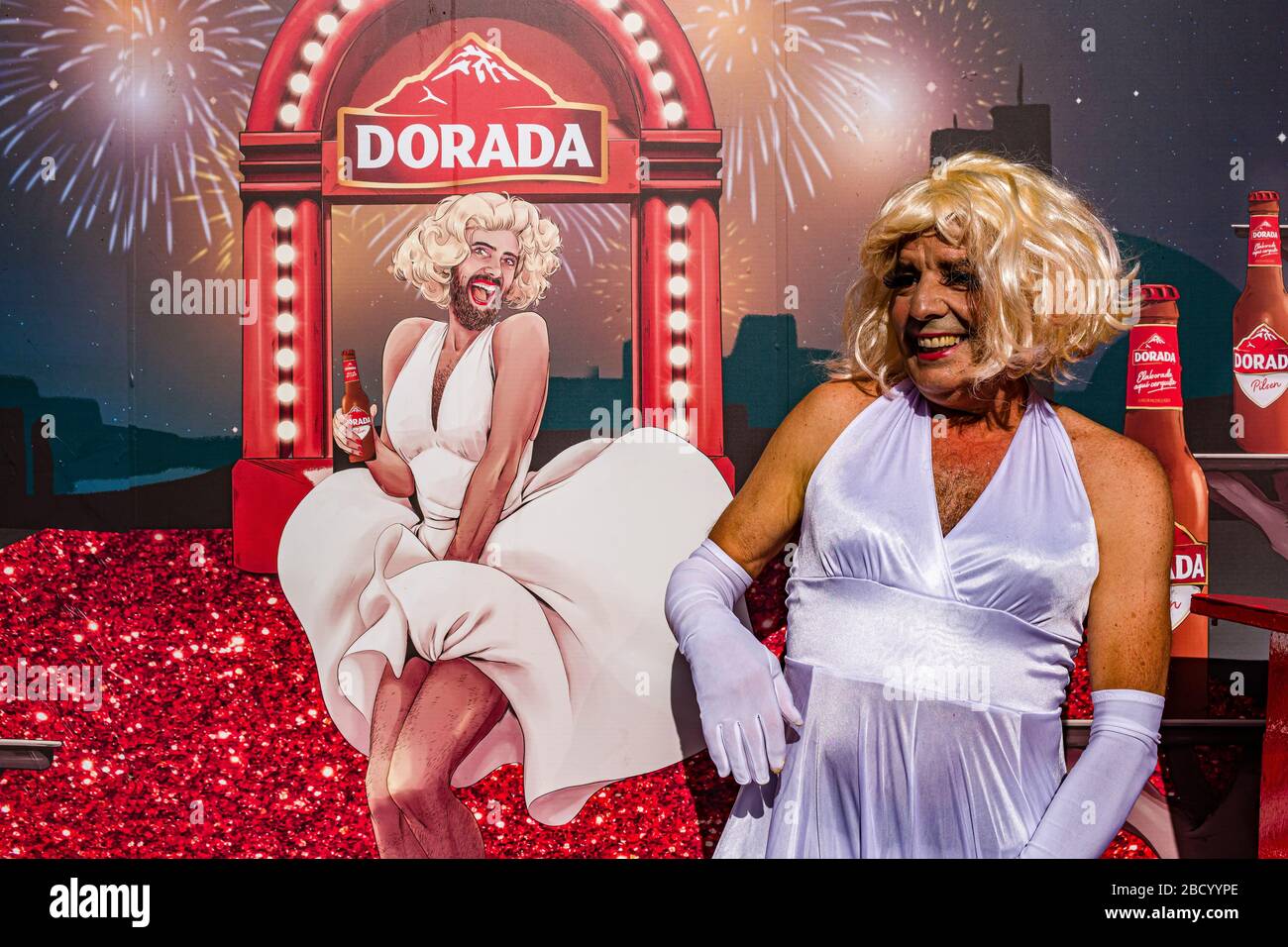 Ein Mann, der als Frau in einem weißen Kleid verkleidet und lächelnd während des Karnevals tagsüber auf der Straße feiert Stockfoto