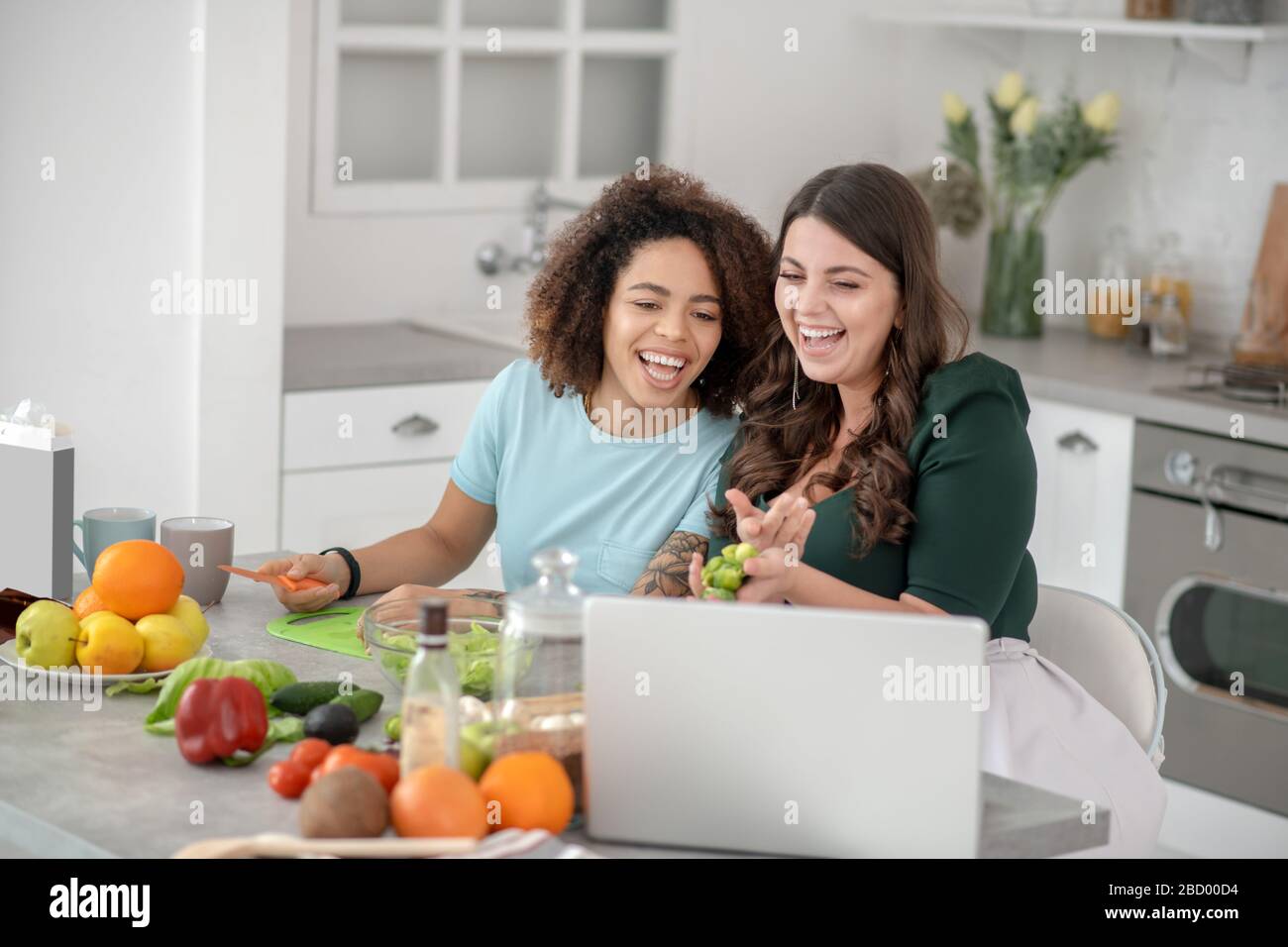 Zwei Freundinnen sitzen an einem Tisch in der Küche. Stockfoto