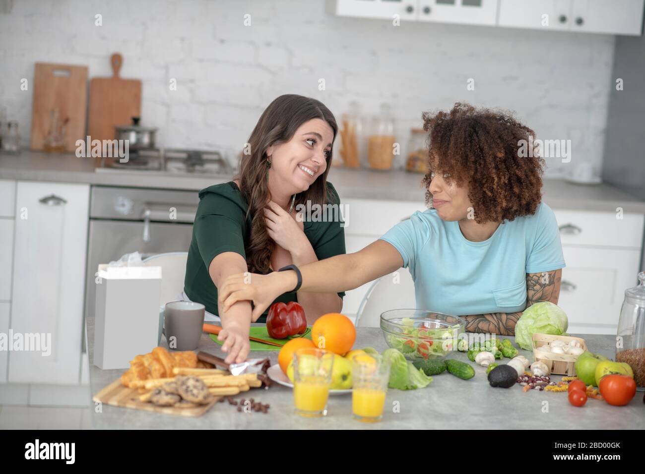 Zwei junge Freundinnen plaudern in der Küche. Stockfoto