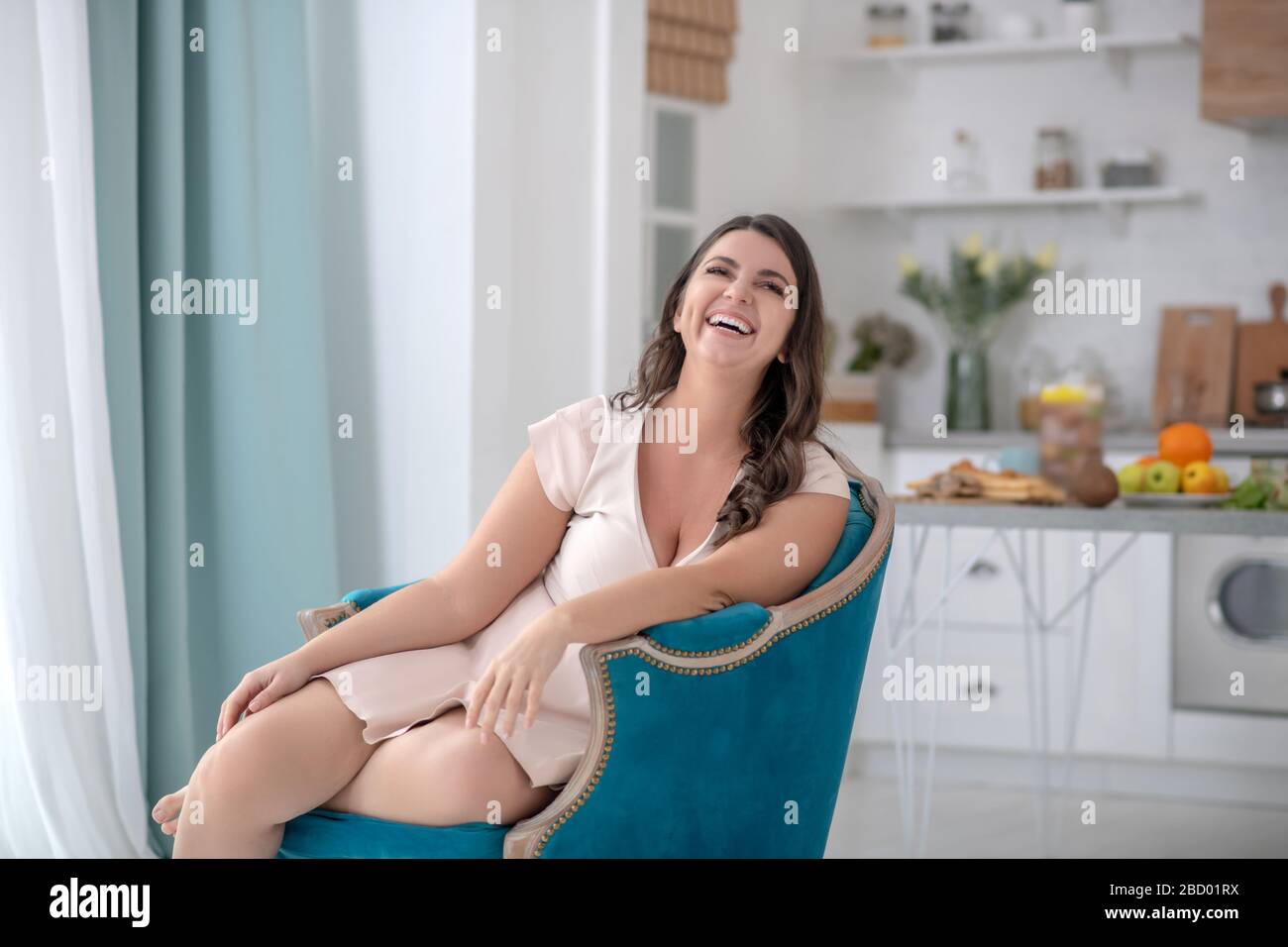 Attraktive junge Frau, die in einem schönen Sessel sitzt. Stockfoto