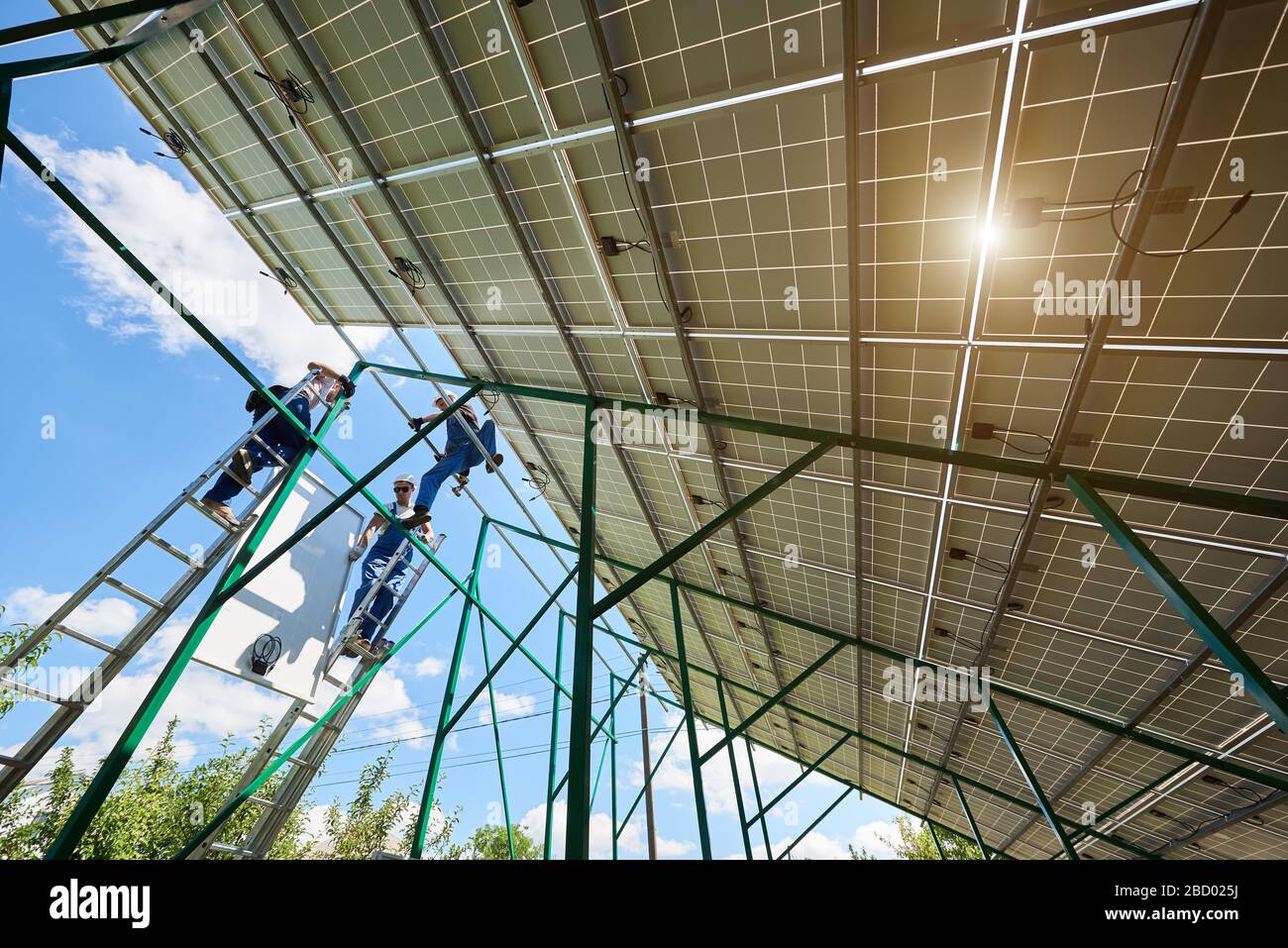 Professionelle Mitarbeiter installieren Solarpaneele auf der grünen Metallkonstruktion mit unterschiedlichen Geräten. Innovative Lösung für die Energielösung. Nutzung erneuerbarer Ressourcen. Grüne Energie. Stockfoto