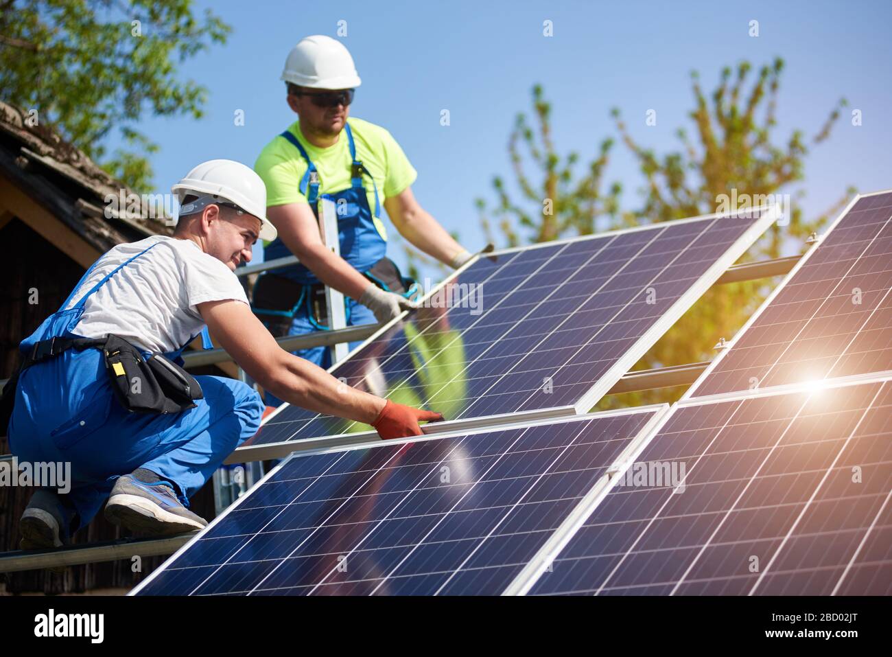 Zwei professionelle Techniker, die schwere Solar-Lichtschnur auf einer hohen Stahlplattform installieren. Installation von externen Solaranlagen, alternatives Konzept zur Erzeugung erneuerbarer grüner Energie. Stockfoto