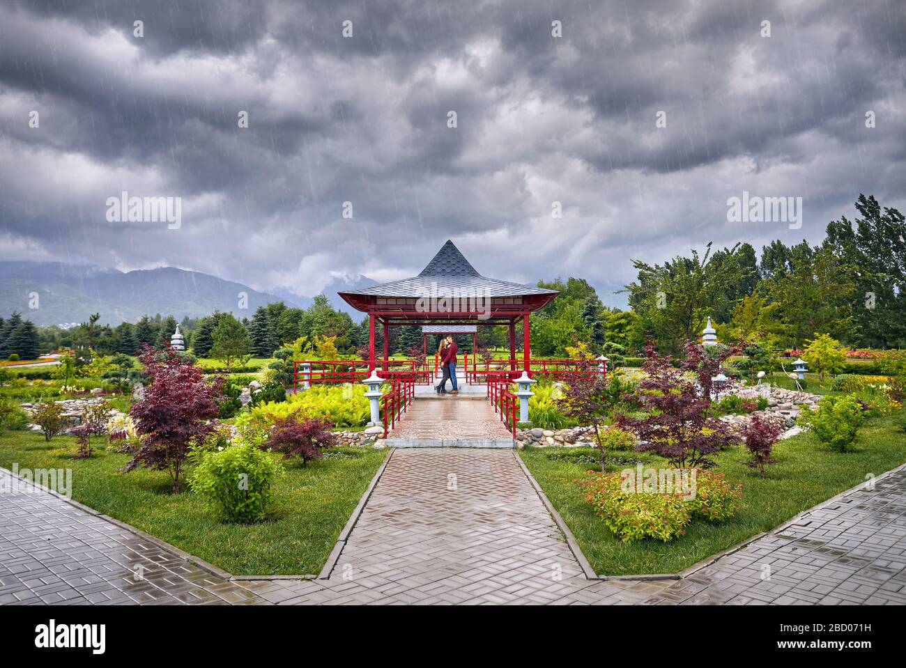 Junges Paar in rot Karo-hemden Umarmen in der Nähe von japanischen Pagode Garten an regnerischen bewölkten Himmel Stockfoto