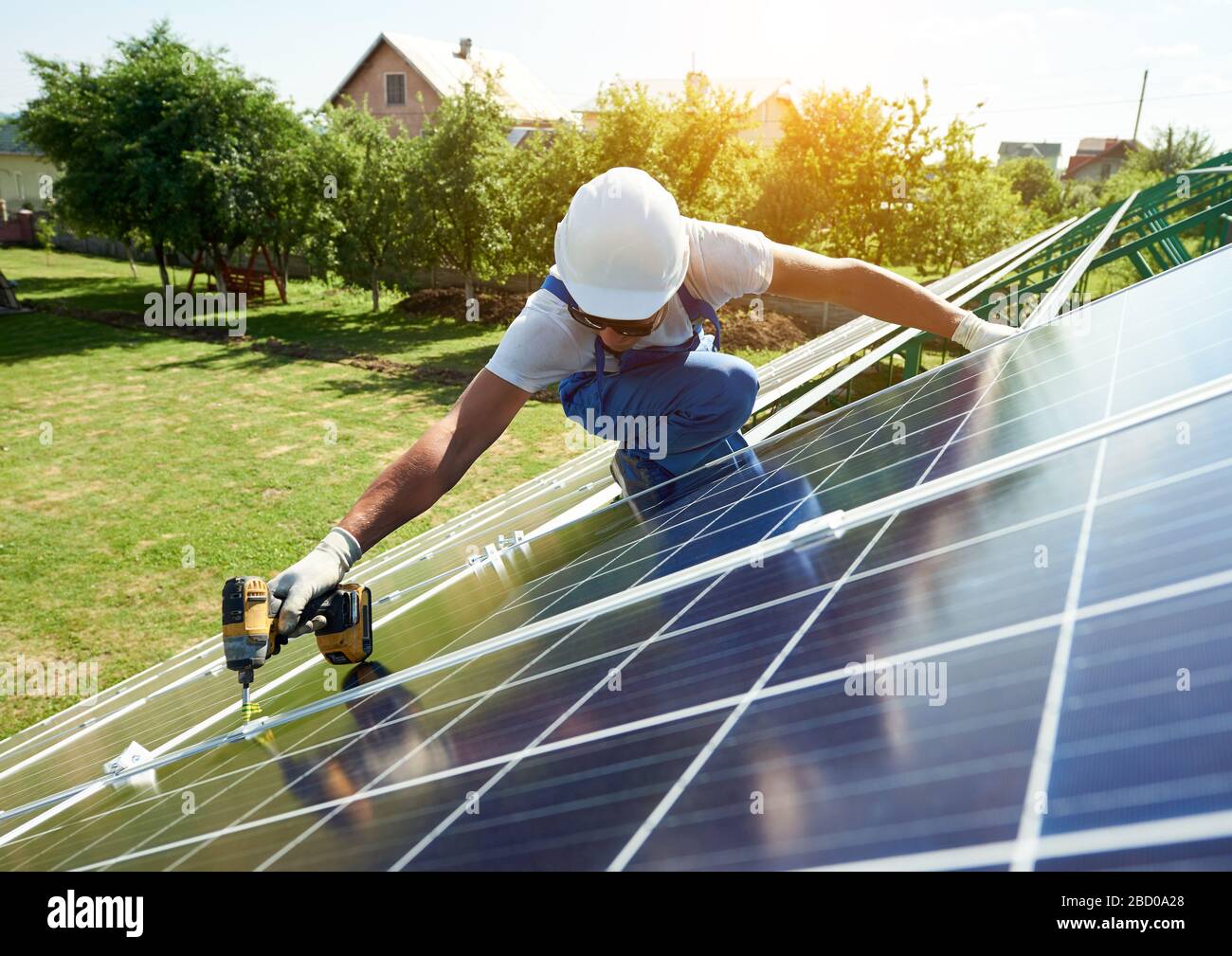 Montage von Solarmodulen für erneuerbare Energien auf dem Dach des Hauses. Mit Spezialausrüstung Schutzhelm tragen. Umweltfreundlich, ressourcenssparend, mit erneuerbarer Solarenergie. Stockfoto