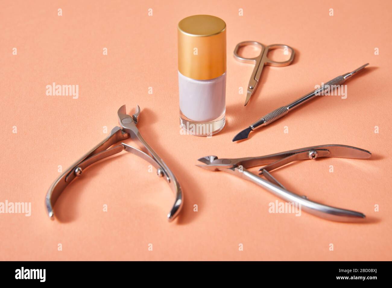 Hochwinkeliger Blick auf die Flasche mit weißem nagellack mit Manikurgeräten auf Korallen Stockfoto