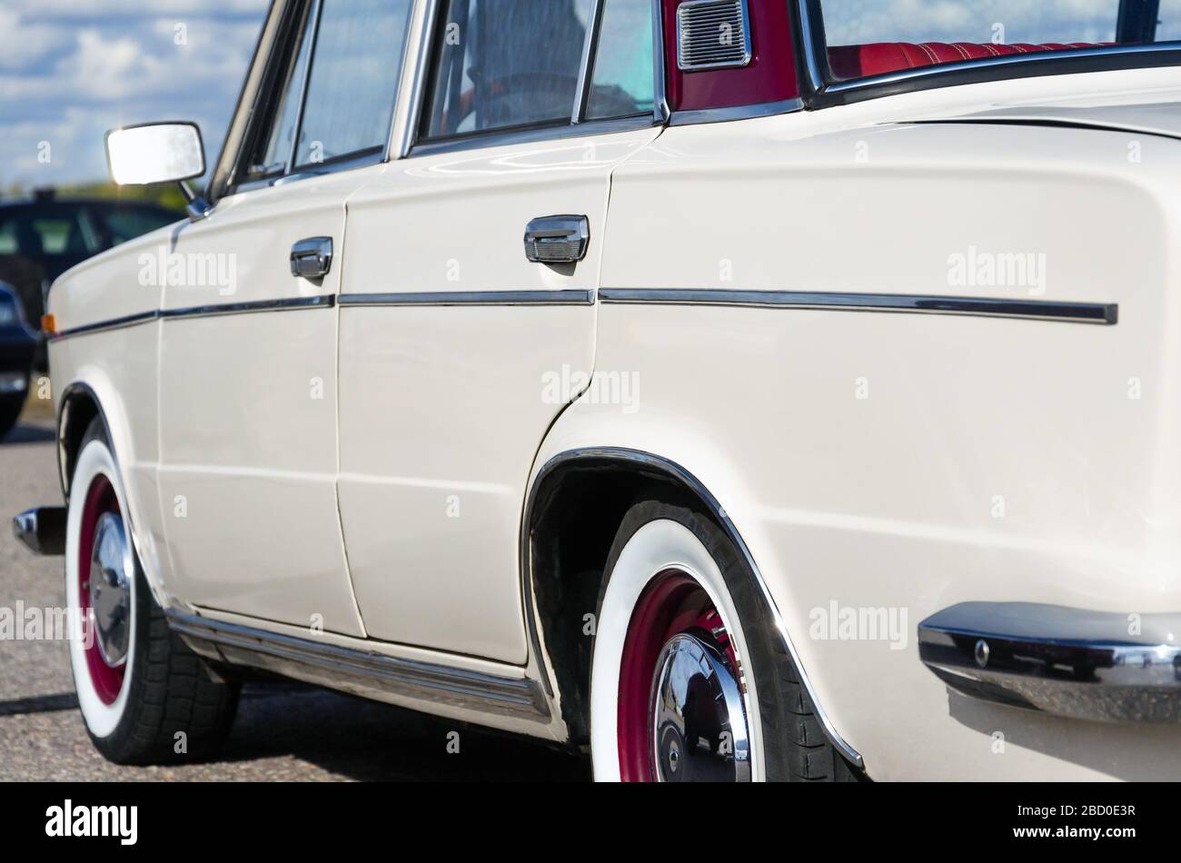 Oldtimer. Beige Retro Auto. Auf den Chrom-Details ein sonniges Highlight. Rückansicht. Sonne gegen den Himmel. Retro Auto Reisekonzept Stockfoto