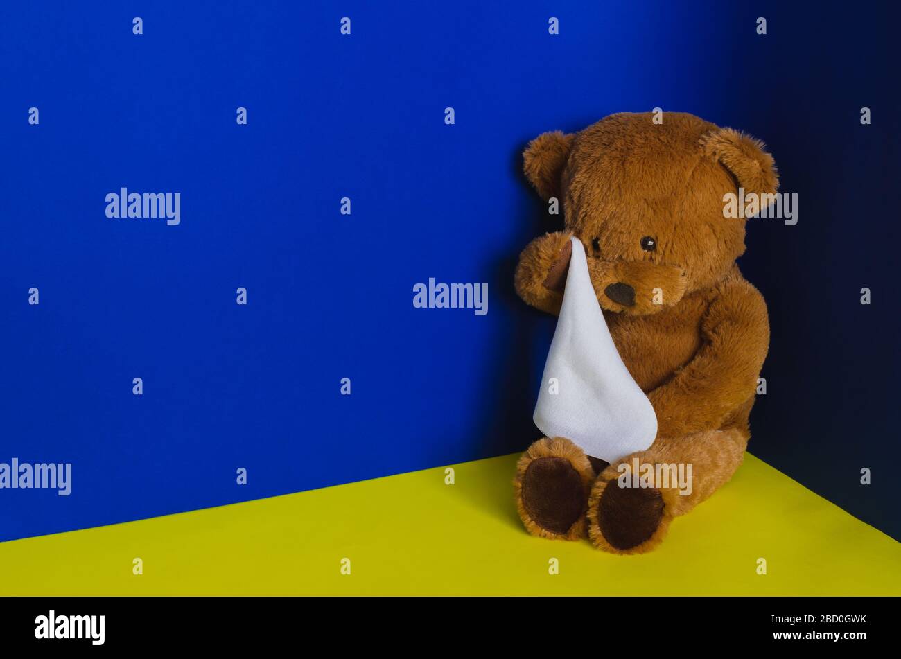 Teddybär-Puppe sitzt an der Ecke und weint mit Taschentuch. Konzept des Kindesmissbrauchs. Stockfoto