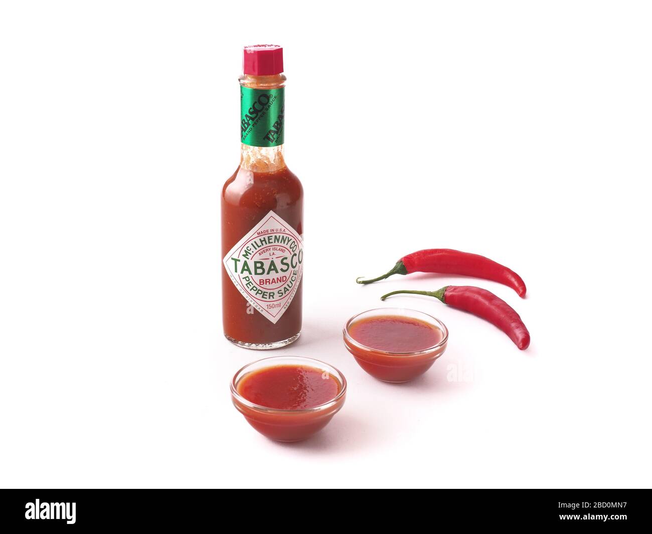 Tabasco Sauce mit gläsernen Schalen voller Soße auf weißem Hintergrund isolierte Zusammensetzung Stockfoto