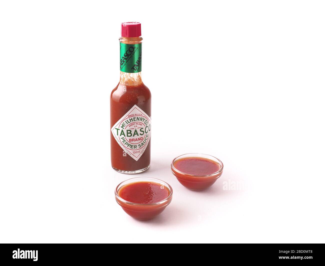 Tabasco Sauce mit gläsernen Schalen voller Soße auf weißem Hintergrund isolierte Zusammensetzung Stockfoto