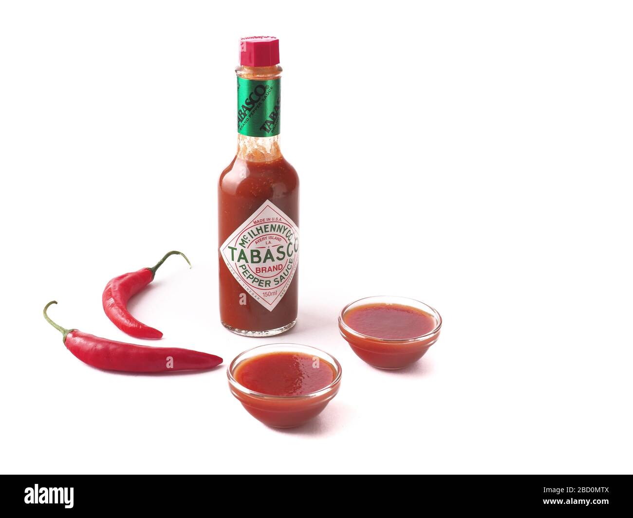 Tabasco Sauce mit gläsernen Schalen voller Soße auf weißem Hintergrund isolierte Zusammensetzung Stockfoto