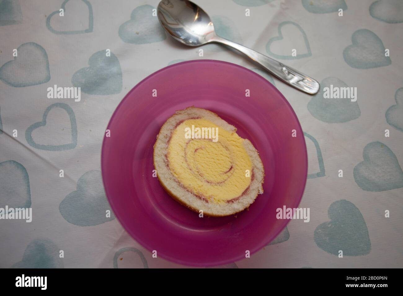 Arctic Roll in einer rosafarbenen Schüssel mit Löffel schneiden Stockfoto