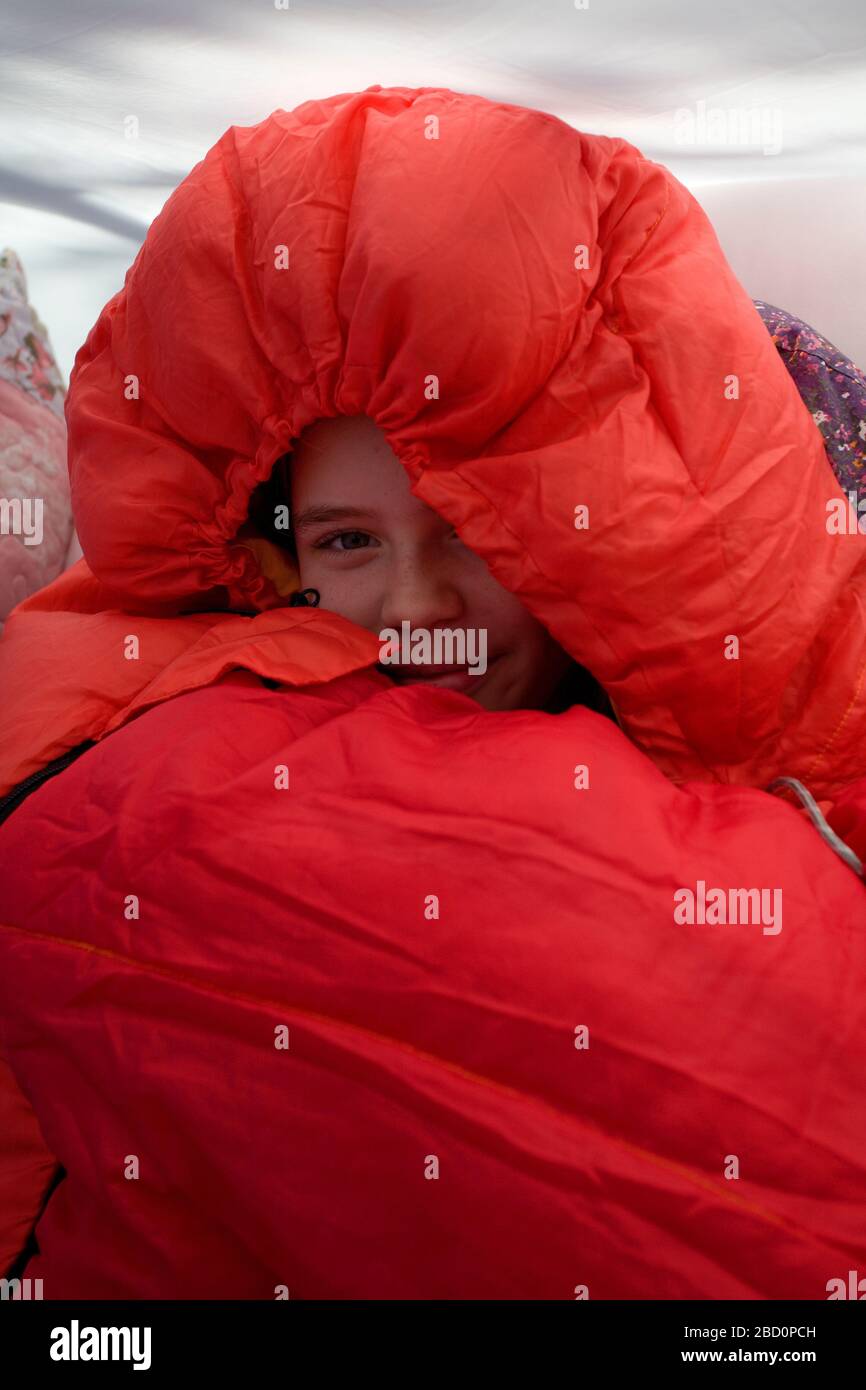Junges Mädchen in ihrem roten Schlafsack mit Kapuze oben Stockfoto