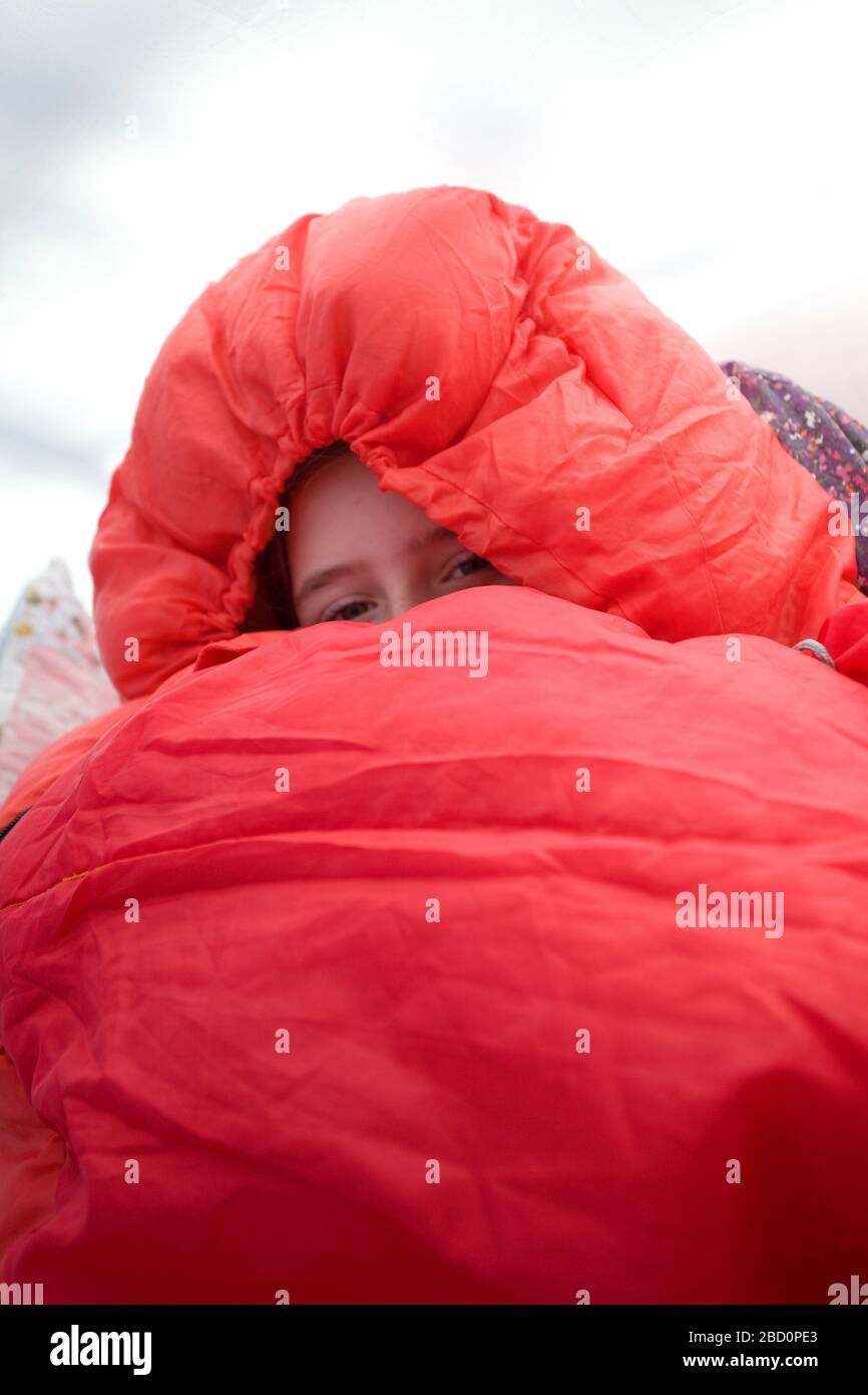 Junges Mädchen in ihrem warmen roten Schlafsack mit Kapuze oben Stockfoto