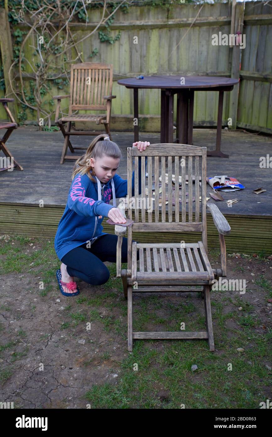 Junges Mädchen schleift Gartenmöbel von außen ab Stockfoto