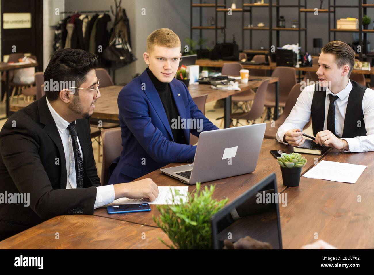 Ein Team junger Geschäftsleute in Anzügen, die in einem Büro zusammenarbeiten und miteinander kommunizieren. Geschäftsleute und Manager in einem Meeting. Stockfoto