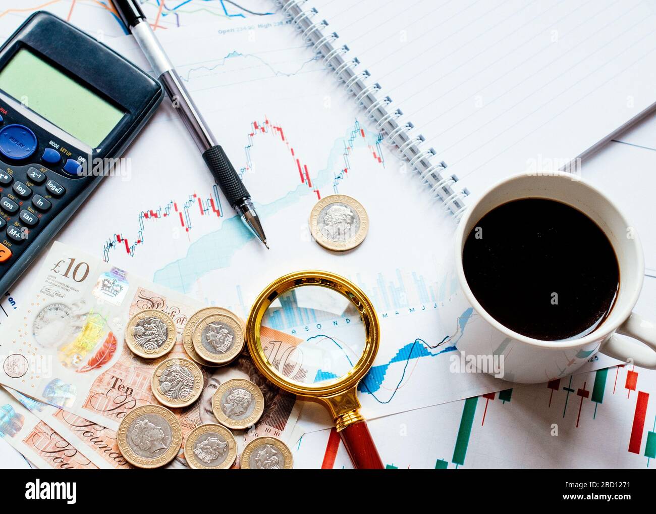 Einige Geldrechner (Pfund, Pfund), eine Kappe Kaffee, Lupe und verschiedene Geldkarten auf dem Tisch. Ansicht von oben. Stockfoto