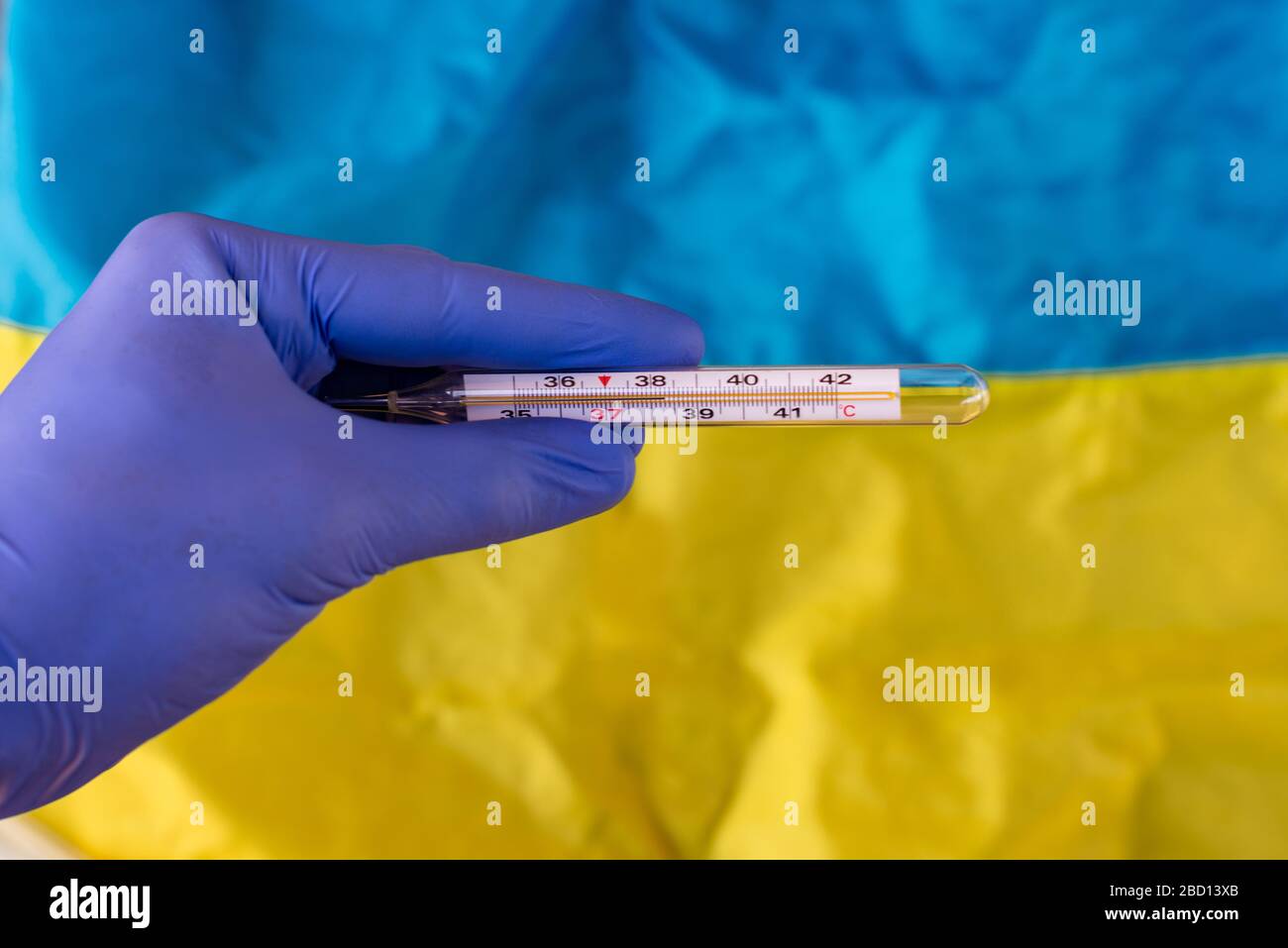 Der Arzt hält ein Thermometer auf dem Hintergrund der ukrainischen Flagge. Die Epidemie der Viruserkrankungen Pandemie in der Ukraine Stockfoto