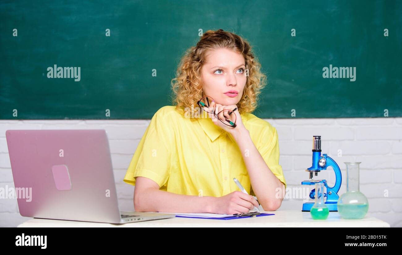 Wissenschaftler im Schullabor. Biologie-Experimentforschung. Denkender Student mit Mikroskop und Becher. Mädchen im Klassenraum mit Computer. Notizen zu den Forschungsergebnissen der Chemie machen. DNA Stockfoto