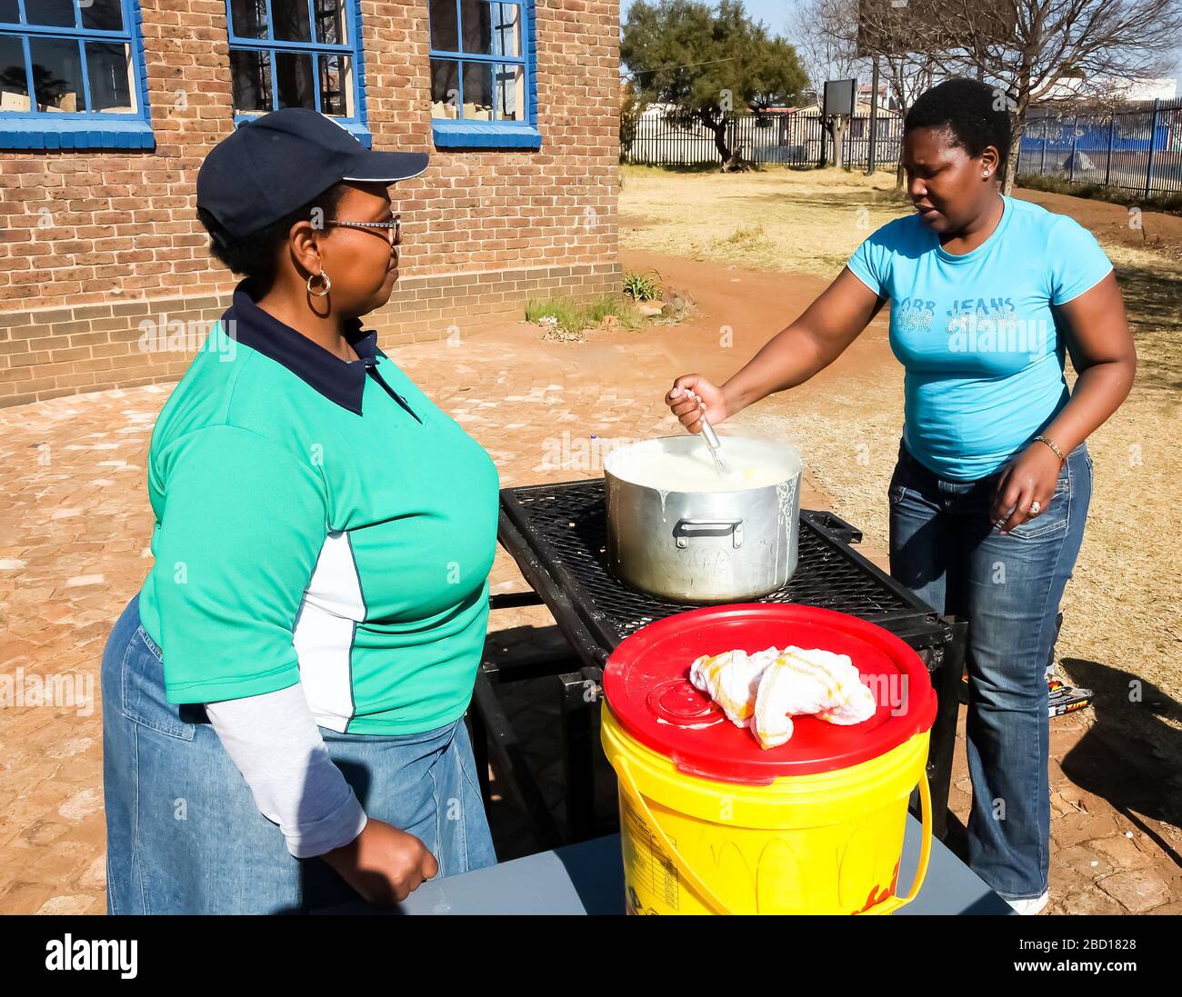 Soweto, Südafrika - 21. Juli 2012: Afrikanische Frau kocht Mielie Pap-Maisbrei auf der Seitenstraße im städtischen Soweto Stockfoto