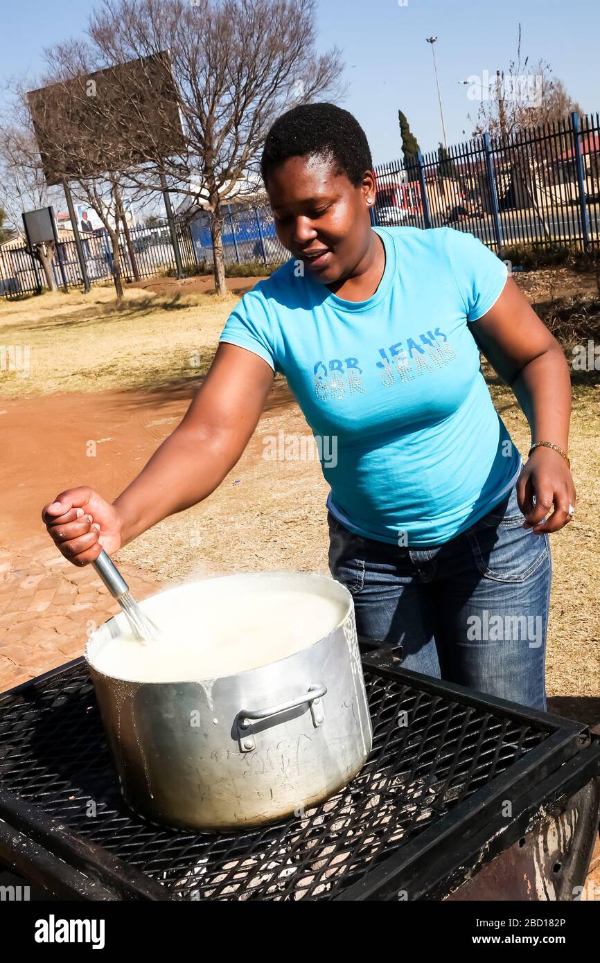 Soweto, Südafrika - 21. Juli 2012: Afrikanische Frau kocht Mielie Pap-Maisbrei auf der Seitenstraße im städtischen Soweto Stockfoto
