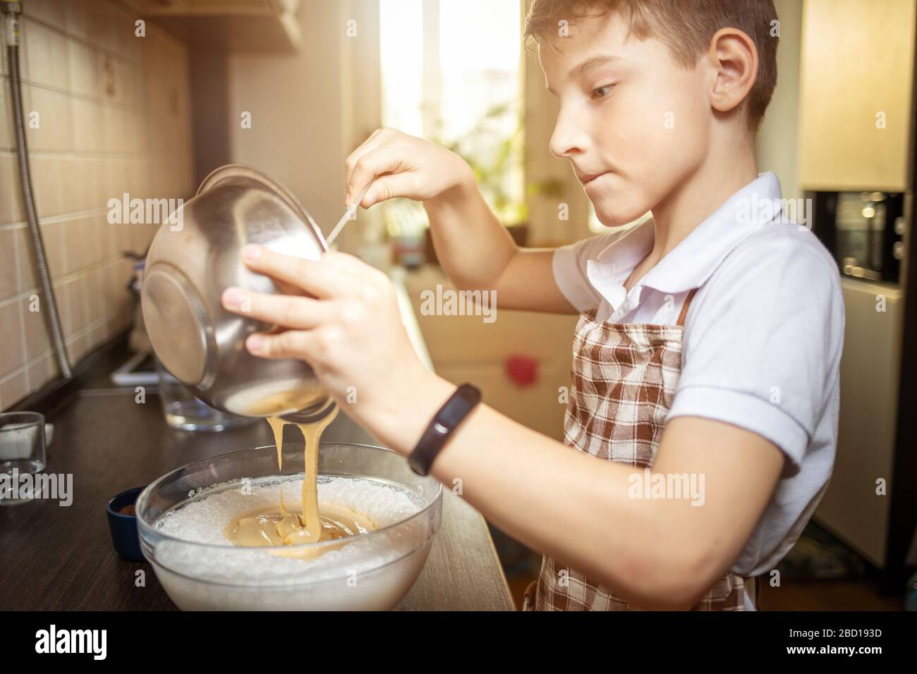 Kleines süßes Dessert zum Kochen von Jungen in der Küche. Familiärer Kochhintergrund. Stockfoto