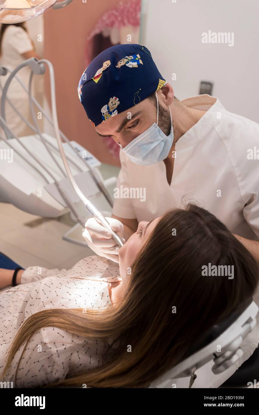 Junge bärtige Zahnärztin bohrt Zahn zu weiblicher Patientin. Stockfoto