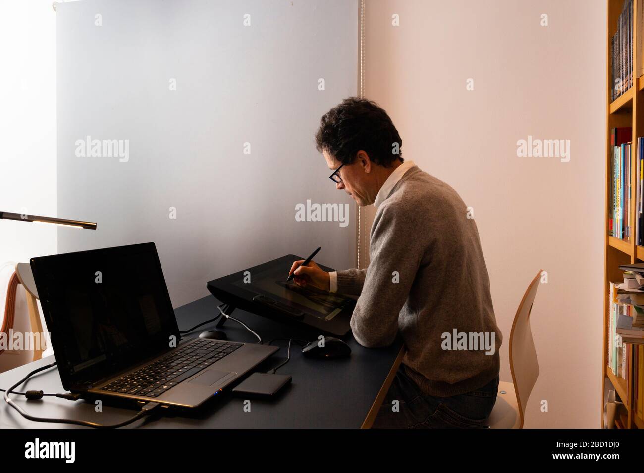 50-jähriger Mann, der zu verschiedenen Tageszeiten zu Hause arbeitet Stockfoto
