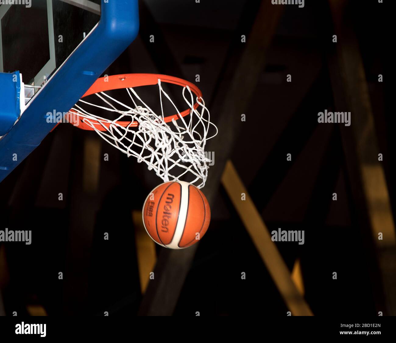 Ein Basketball, der auf einem Basketballplatz durch den Reifen fällt. Stockfoto