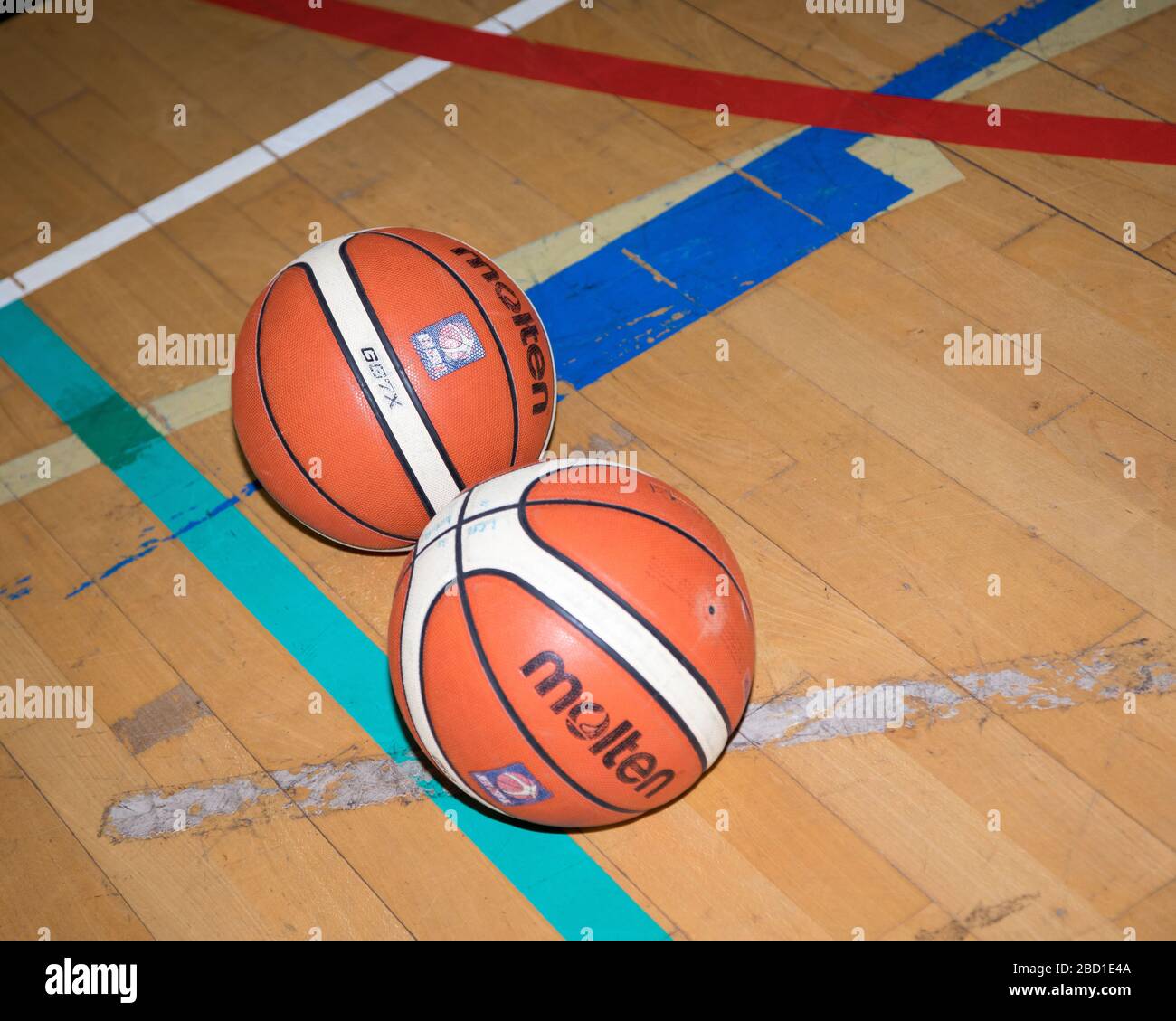 Zwei Korbbälle sitzen auf den Holzbrettern des Basketballhofs Stockfoto