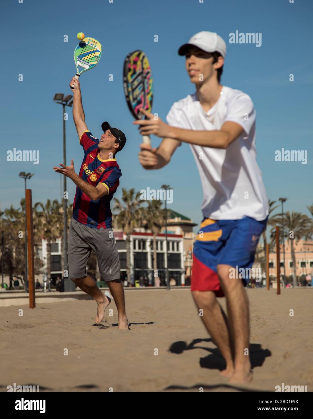 Zwei Männer in Aktion spielen Doppel Beach Tennis mit sonnigen, blauen Himmel und auf goldenem Sand. Stockfoto