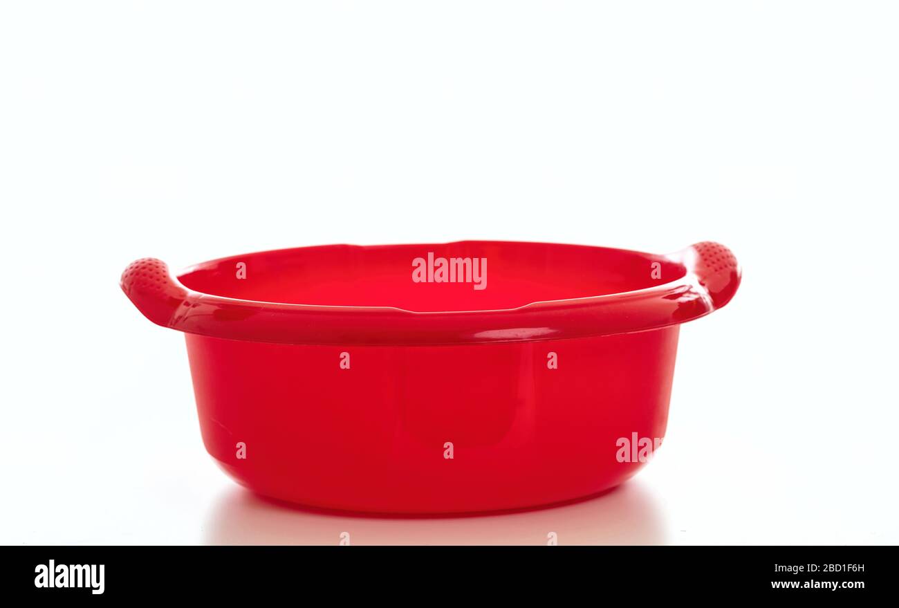 Reinigungswaschbehälter, rote Farbe des Handbassins aus Kunststoff, isoliert vor weißem Hintergrund, Haushaltsreinigung im Haushalt Stockfoto