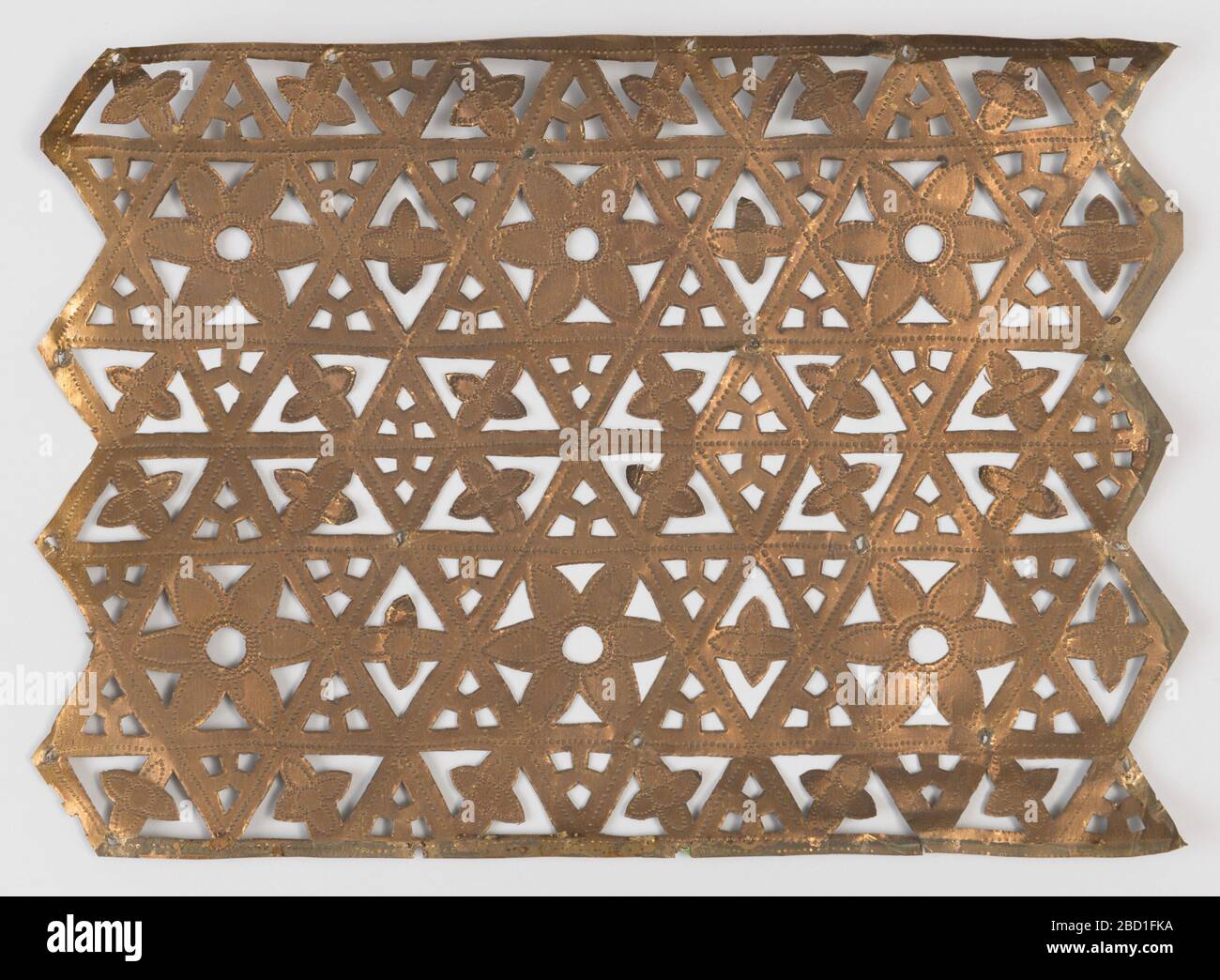 Ausschnitt. Das rechteckige Blatt aus dünnem Kupfer mit seitlichen spitzen Rändern, durchbohrt mit einer Anordnung von Dreiecken und Blumenköpfen in einem geometrischen Muster Ausschnitt Stockfoto