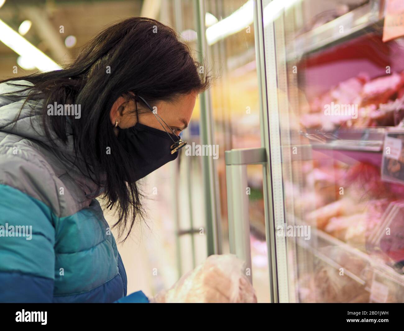 Frau mit Schutzmaske im Gesicht kauft während einer Coronavir-Pandemie in einem Einkaufszentrum Stockfoto