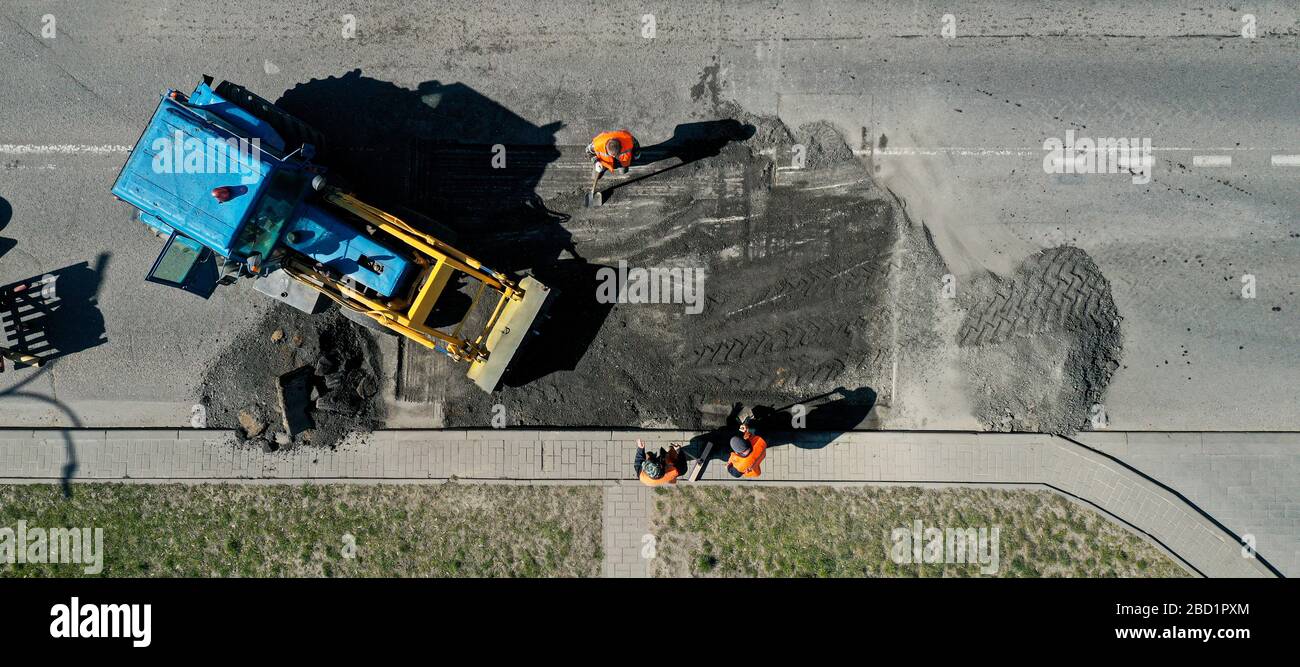 Luftbild der Straßenarbeiter repariert Asphaltbelag. Teamwork-Konzept. Kontrast zwischen neuer und alter Fahrbahn. Stockfoto