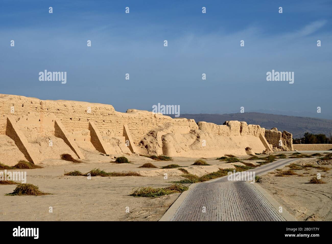 Straße vorbei an der zerstörten Stadtmauer der alten Seidenstraßenstadt Gaochang, Taklamakan-Wüste, Xinjiang, China, Asien Stockfoto