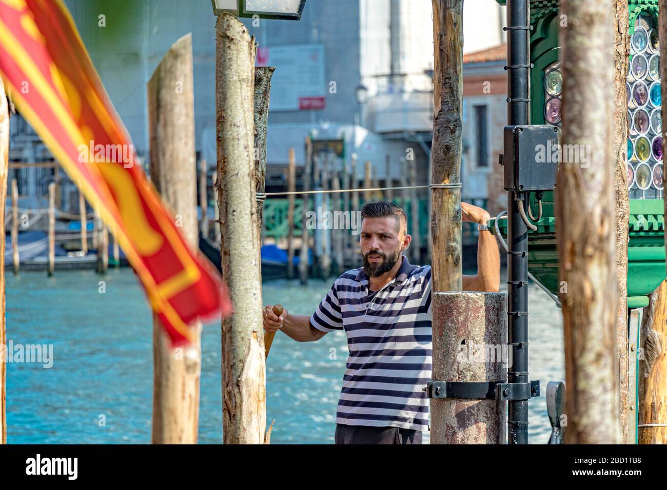 Ein Gondolier, der eine Pause einlegt, ruht seine RM gegen einen hölzernen Ankerpfosten auf dem Canal Grande, Venedig Stockfoto