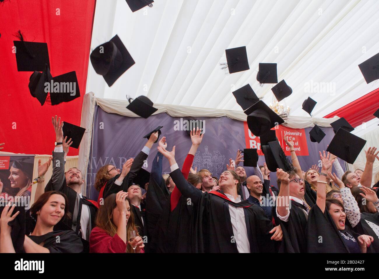 Studenten feiern den Abschluss, indem sie ihre Mörtelbretter in die Luft werfen Stockfoto
