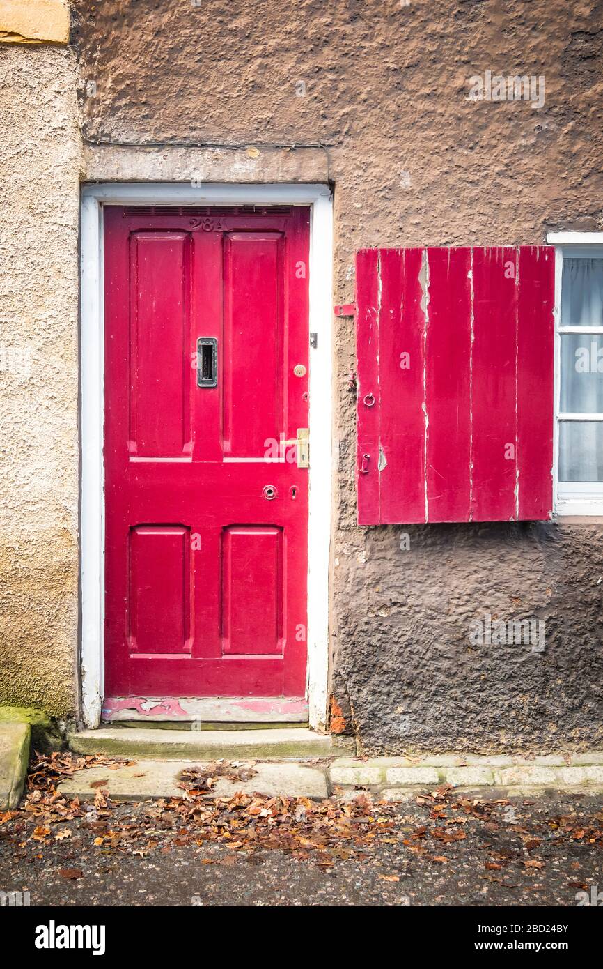 Eine alte rot lackierte Tür und passende Fensterläden Stockfoto