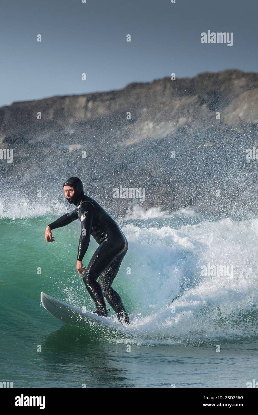 Ein reifer männlicher Surfer, der eine Welle bei Fistral in Newquay in Cornwall reitet. Stockfoto