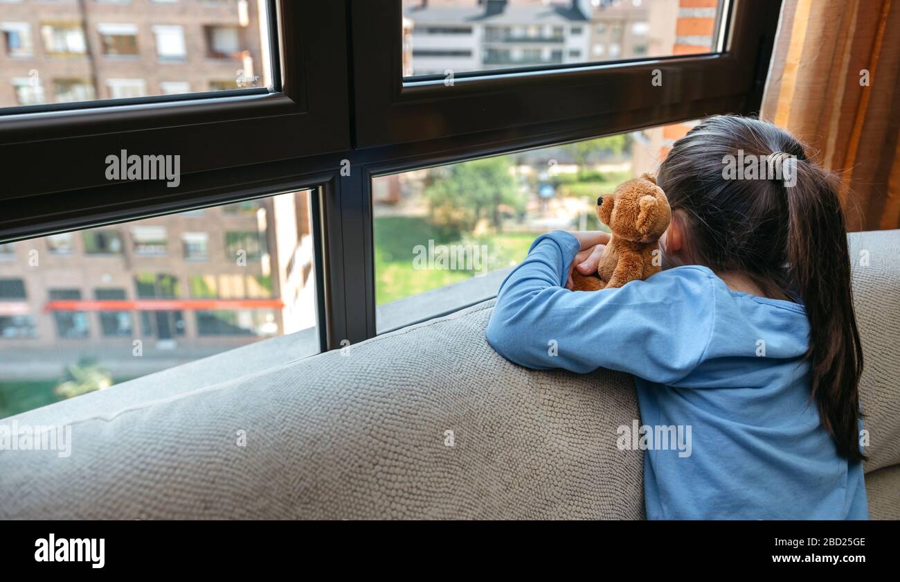 Unerkennbares trauriges Mädchen mit Blick auf das Fenster Stockfoto