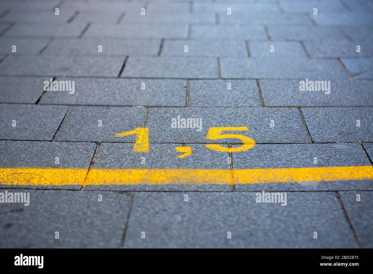 Gelbe Markierung auf der Straße, um die soziale Distanz durch das Coronavirus oder die Covid-19-Pandemie zu lenken Stockfoto