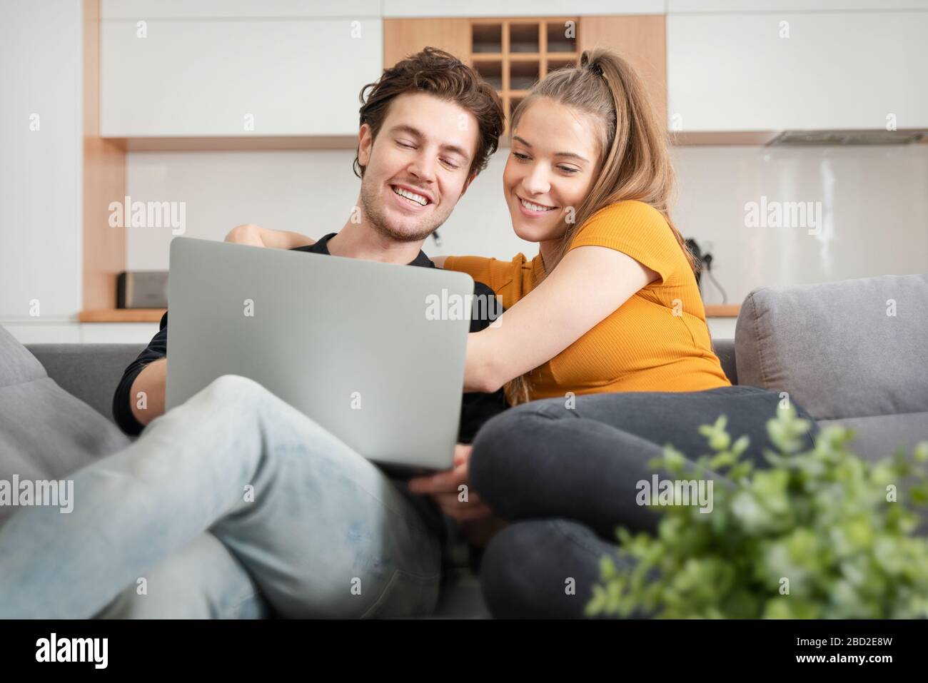Verbinden Sie das Gerät mit dem schnellen Internet zu Hause mit einem Laptop. Frau und Mann auf dem Sofa im Wohnzimmer Stockfoto