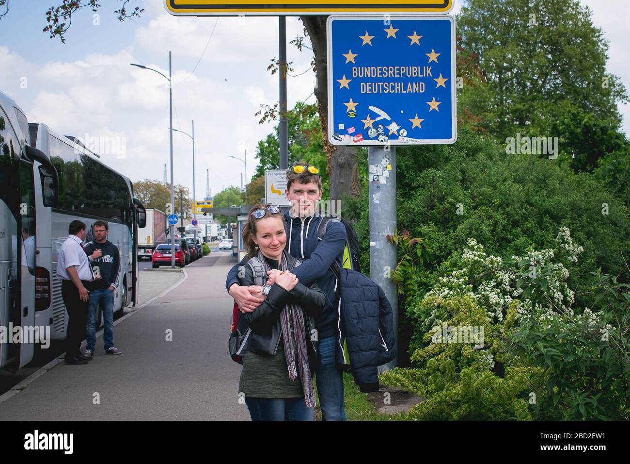 Junge Leute überqueren eine deutsche Grenze, stehen neben dem Schild. Stockfoto