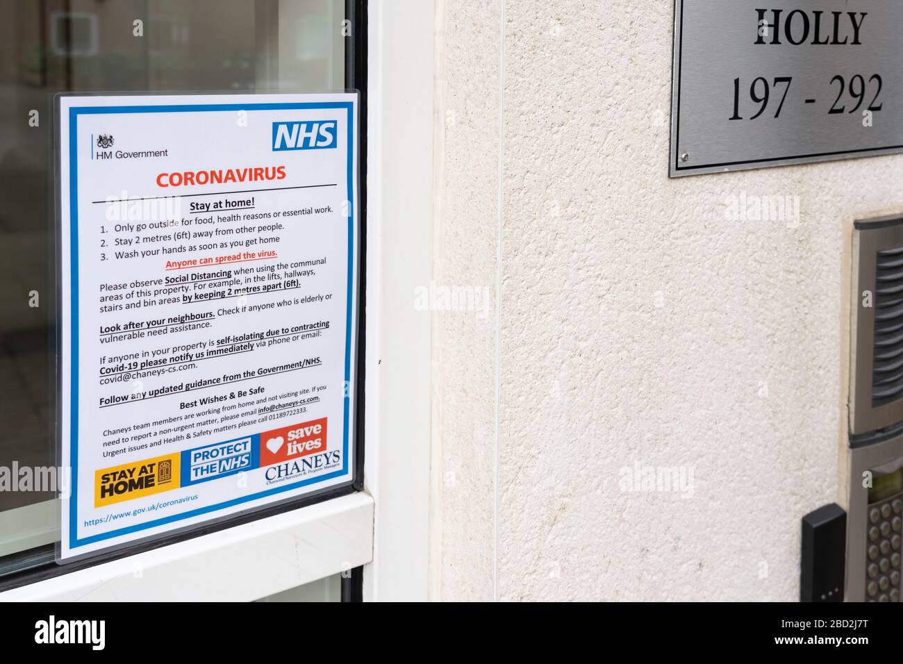 Eine offizielle Regierungsmitteilung neben einem öffentlichen Eingang für Wohnungen, in der die Öffentlichkeit darauf hingewiesen wird, während der Pandemie von Coronavirus im April 2020 in Großbritannien zu Hause zu bleiben Stockfoto