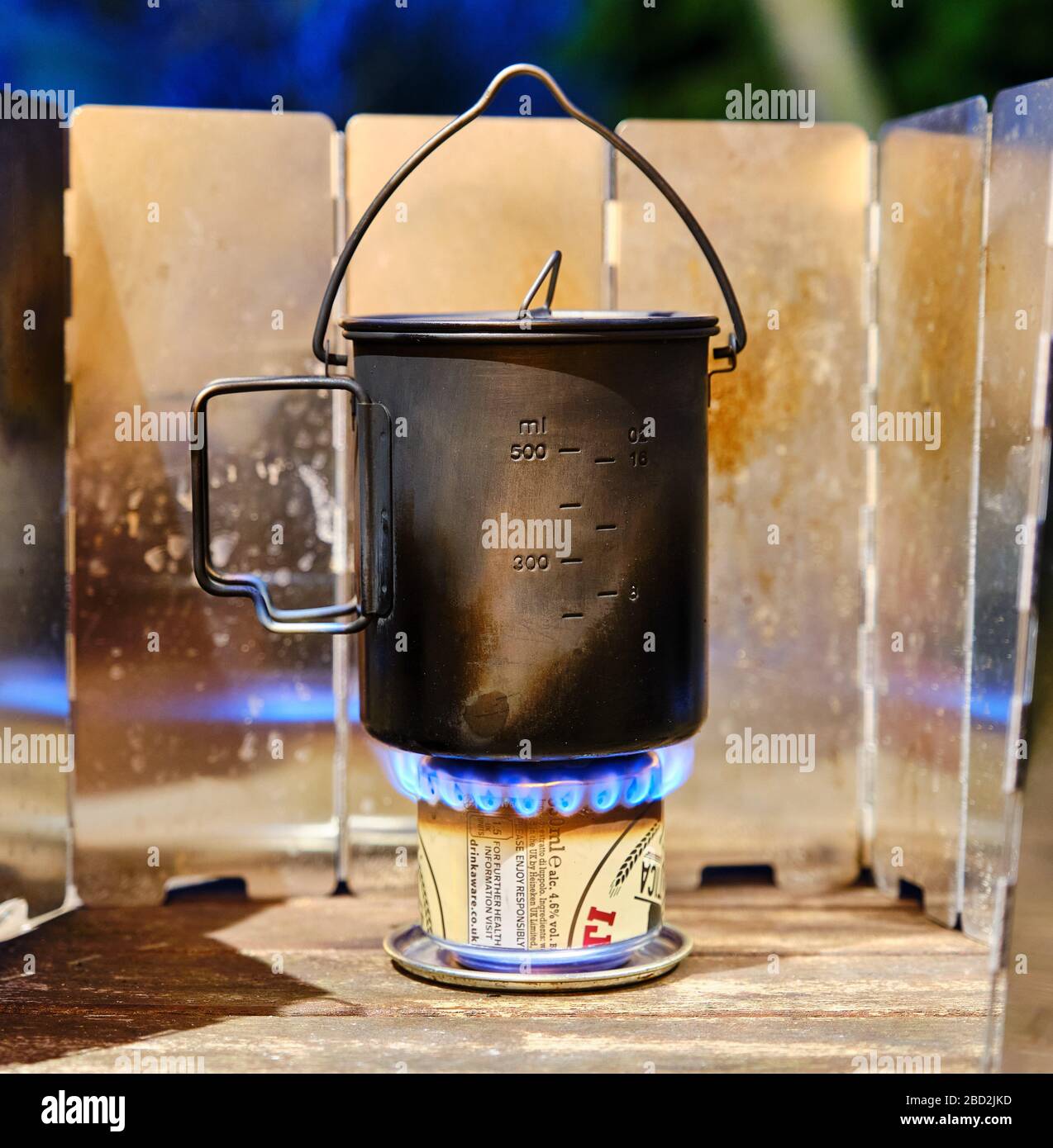 Wasser, das in einem leichten Titan-Topf auf einem improvisierten hausgemachten Pfennig-Herd-Pop gekocht wird, kann Bier Hobo-Spiritbrenner bringen Stockfoto