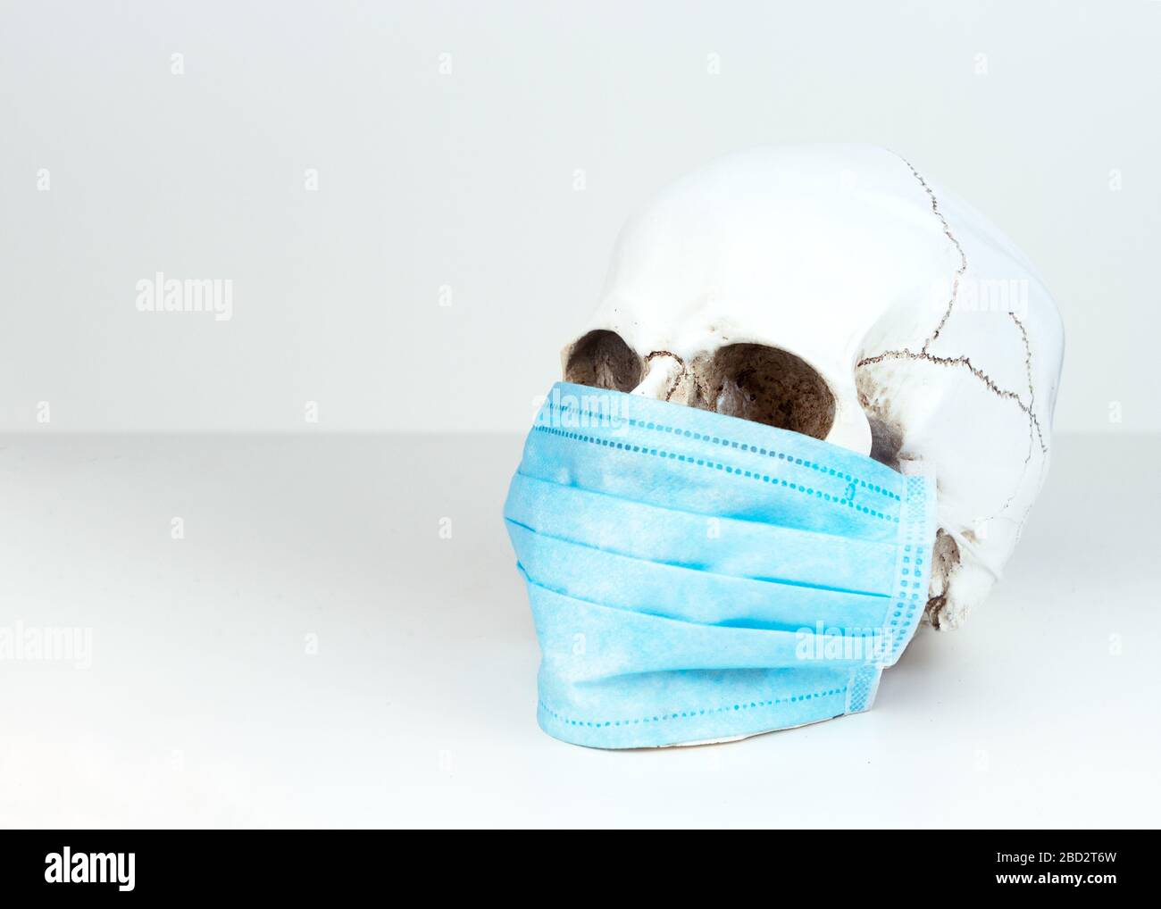 Ein menschlicher Schädel in einer medizinischen Maske. Konzept der Sterblichkeit durch Coronavirus, Infektion mit einem tödlichen Virus, Stockfoto