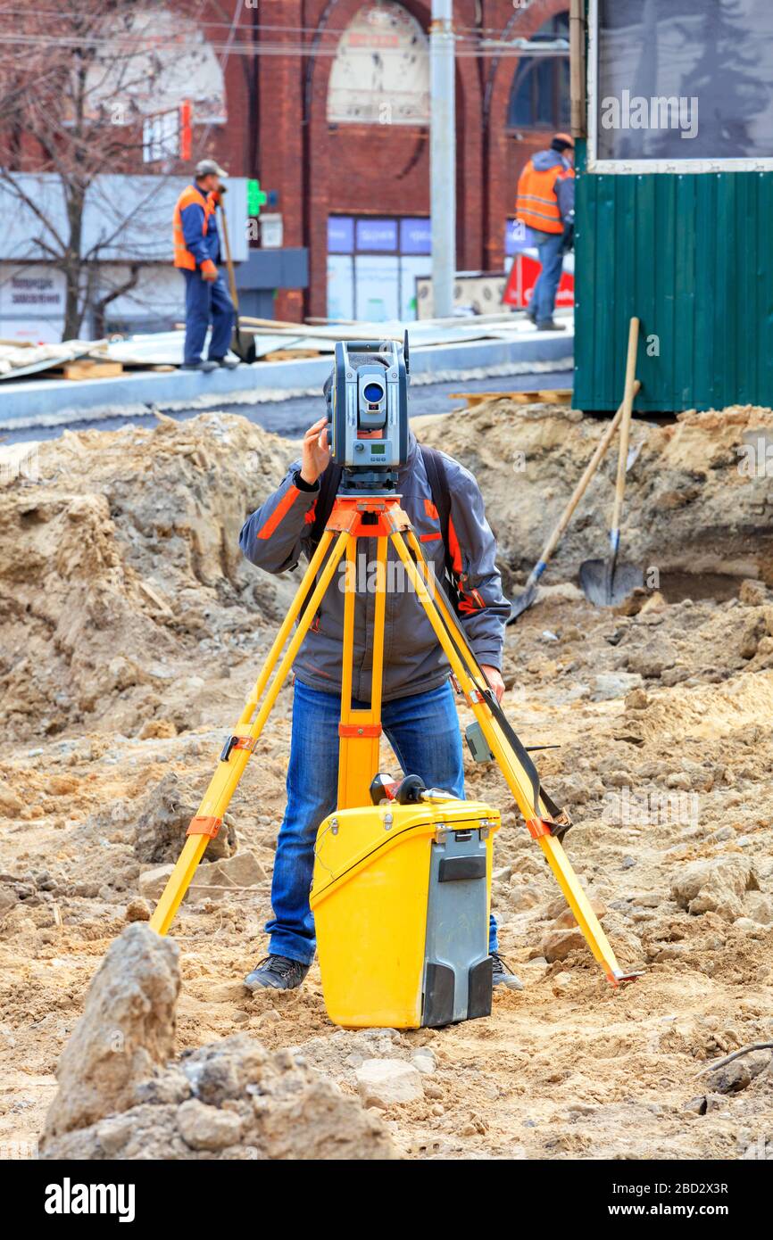 Der Verkehrsingenieur ermittelt anhand des Laserpegels den erforderlichen Neigungswinkel des im Bau befindlichen Straßenabschnitts. Stockfoto