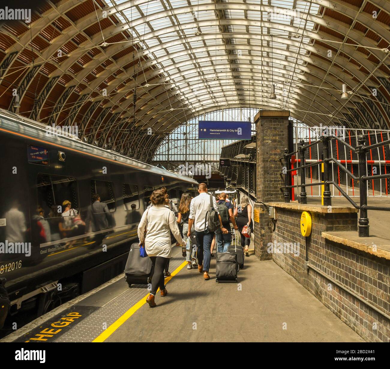 LONDON, ENGLAND - JULI 2018: Menschen, die auf einem Bahnsteig am Bahnhof London Paddington spazieren, um einen Zug zu nehmen Stockfoto